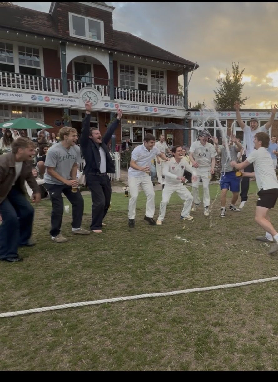 Players celebrating a win with a champagne spray by the pavilion